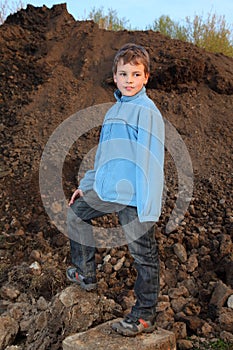Little boy stands on earthen embankment