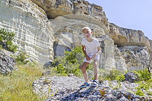 little boy stands on rock in the mountains and growls like a dinosaur or a zombie