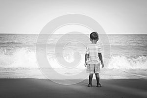 Little boy stanging looking the sea,black and white tone photo