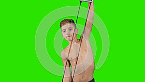 Little boy stretches elastic expander at green background