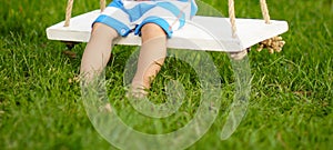 Little boy in a striped bodyguard swings on a swing