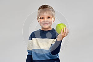 Little boy in striped pullover with green apple