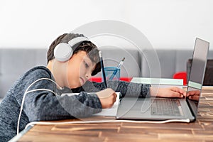 Little boy is studying in front of the laptop. E learning, study at home online.
