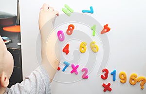 A little boy is studying the magnetic numbers on the fridge. Preschooler training