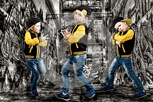 The little boy in the style of Hip-Hop . Children`s fashion.Cap and jacket. The Young Rapper.Graffiti on the walls.Cool rap dj.