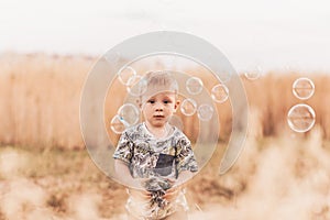 Little boy in the summer in nature playing with soap bubbles