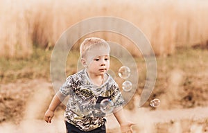 Little boy in the summer in nature playing with soap bubbles