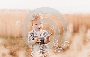 Little boy in the summer in nature playing with soap bubbles