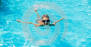 Little boy in sunglasses swimming in the pool having fun, Happy child playing in the pool, Summer vacation concept, Top portrait