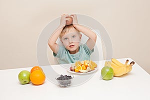 A little boy surround by fruit. The child is photographed again