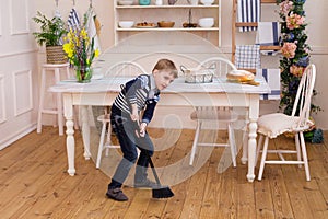 Little boy sweeping the floor. Pretty boy cleaning the kitchen w