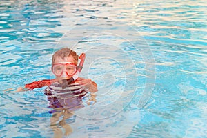 Little boy swimming with mask in outdoor pool