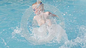 Little boy in swimming pool, child having fun, sitting on blue swimming ring, playing under water. Summer travel family