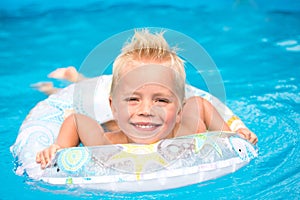little boy is swimming in swimming pool with inflable ring photo