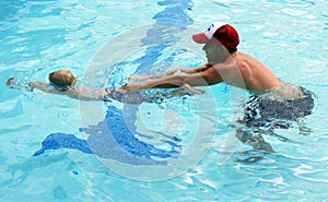 Little boy swimming with swim instructor