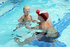 Little boy swimming with swim instructor