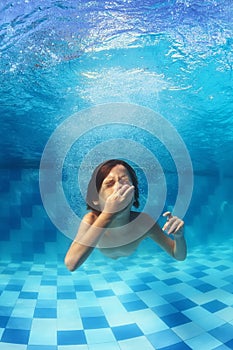 Little boy swimming underwater in the blue pool