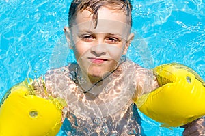 Little boy swimming in the water with armbands