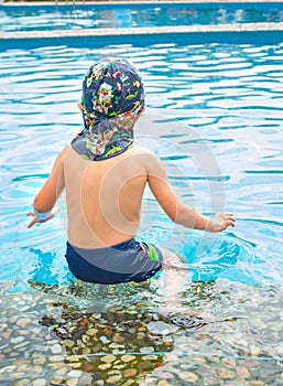 Little boy swims, cheerful child jumping in the pool in the circle, open-air swimming pool,