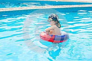 Little boy swims, cheerful child jumping in the pool in the circle, open-air swimming pool,