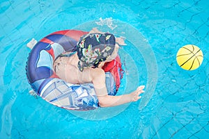 Little boy swims, cheerful child jumping in the pool in the circle, open-air swimming pool,