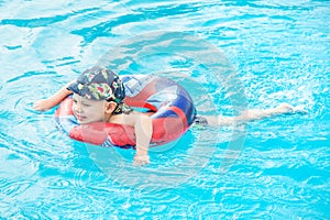 Little boy swims, cheerful child jumping in the pool in the circle, open-air swimming pool,