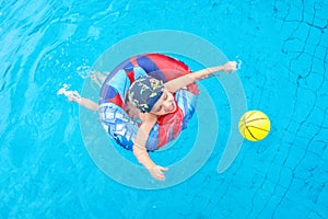 Little boy swims, cheerful child jumping in the pool in the circle, open-air swimming pool,