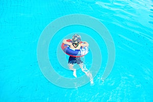 Little boy swims, cheerful child jumping in the pool in the circle, open-air swimming pool,