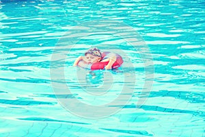 Little boy swims, cheerful child jumping in the pool in the circle, open-air swimming pool,