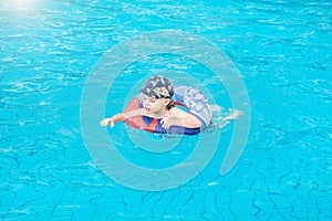 Little boy swims, cheerful child jumping in the pool in the circle, open-air swimming pool,