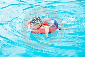 Little boy swims, cheerful child jumping in the pool in the circle, open-air swimming pool,