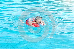 Little boy swims, cheerful child jumping in the pool in the circle, open-air swimming pool,