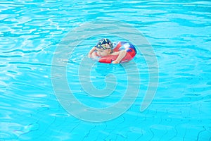 Little boy swims, cheerful child jumping in the pool in the circle, open-air swimming pool,