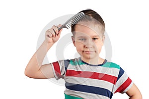 Little boy in a T-shirt combing his hair, isolated on white background