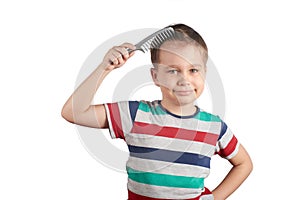 Little boy in a T-shirt combing his hair, isolated on white background