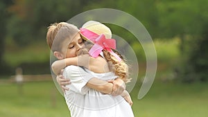 Little boy takes the girl in her arms and they so spin around in the park. Slow motion