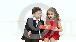 Little boy takes a pair of pants and gives the girl in return she kisses him on the cheek. White background