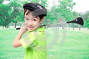 Little boy taking golf club at golf course background