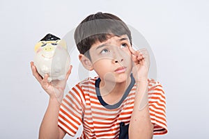 Little boy taking hammer thinking and trying to broke piggy bank