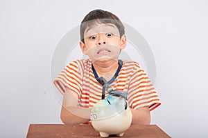 Little boy taking hammer trying to broke piggy bank on the table