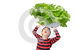 Little boy taking huge big bowl of vegetable over his head on white background