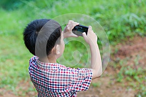 Little boy taking photos by digital camera on smartphone