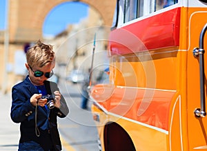 Little boy taking photos of traditional bus in