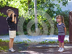 Little boy taking the picture of a litthe girl on sunny summer d