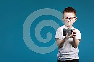 Little boy taking a picture using a retro camera. Child boy with vintage photo camera isolated on blue background. Old