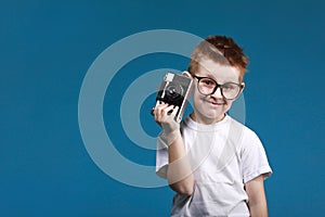Little boy taking a picture using a retro camera. Child boy with vintage photo camera isolated on blue background. Old