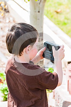 Little boy taking pictures with an old camera