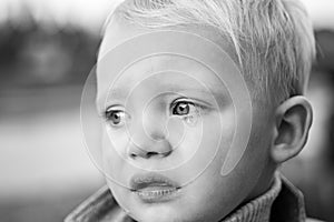 Little boy with tears close up defocused background. Emotional sad baby. Toddler sad face crying. Sad emotions. Hard to