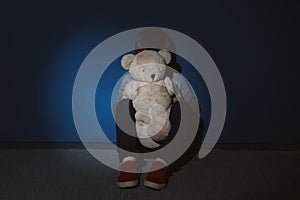 Little boy with teddy bear near wall. Domestic violence concept