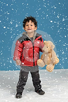 Little boy with teddy bear in the snow